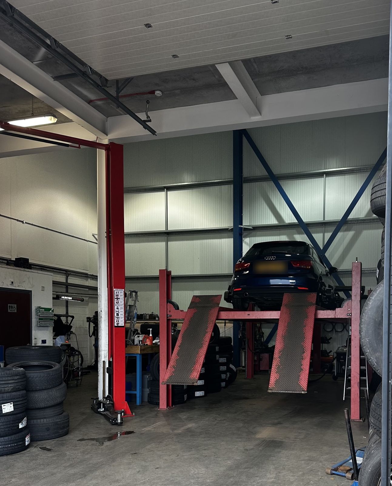 A blue Audi on the alignment ramp, with tyres racked along the wall