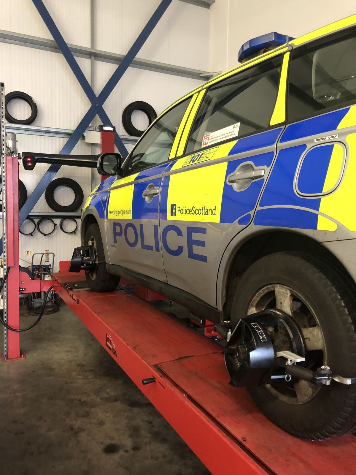 A Police Scotland car on the alignment ramp with clamps fitted to the wheels