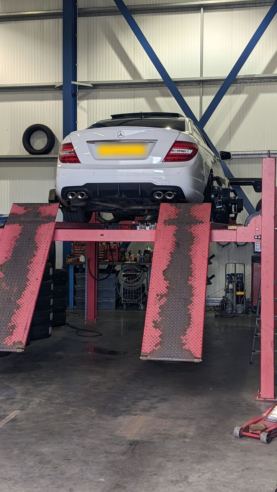 A white Mercedes up on the lift in the Ayrshire Alignment workshop